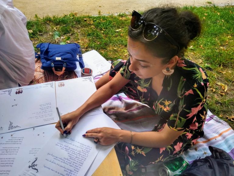Carla Francesca Schoppel scriind într-un jurnal, în aer liber